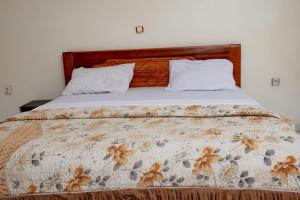 a bed with a floral comforter and two pillows at Elegant Villa Apart in Kigali +8 photos