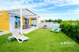 a yard with two chairs and a house at SOLEO Family Resort - domki 3 min od Morza - 3 Baseny, 3 Jacuzzi, Sauna, ANIMACJE, Małpi Gaj, 3 Sale Zabaw, 4 Place Zabaw, 2 Restauracje in Rewal
