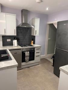 eine Küche mit weißen Schränken und einem Herd mit Backofen in der Unterkunft Leamington Spa Town House, cosy central house in Leamington Spa