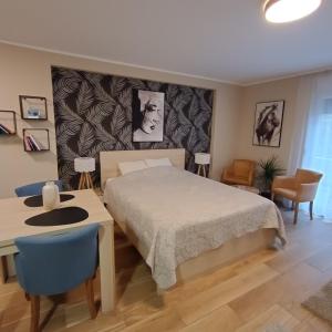 Vrnjačka BanjaにあるAPARTMANI PORTA INFINITAS centarのベッドとテーブルと椅子のある寝室 +255枚の写真