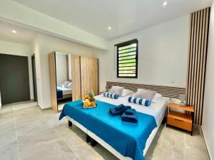 a bedroom with a large bed with a blue blanket at Villa Aloha - classée 5 étoiles - avec piscine in Les Trois-Îlets