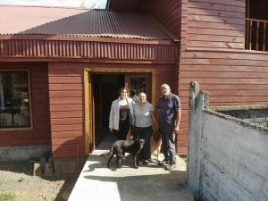 Drei Personen und ein Hund stehen vor einem Haus in der Unterkunft Hostal Rama Fueguina in Teodoro Schmidt + 11 Fotos
