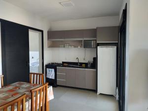 a kitchen with a refrigerator and a table with chairs at Paraiso das ondas primeira quadra do mar in Balneário Gaivotas