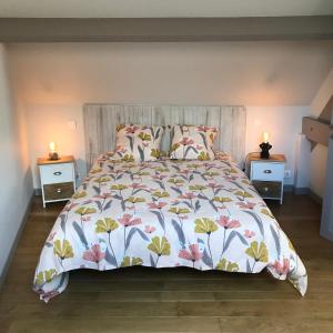 a bed with a floral bedspread and two night stands at Maison en pierre in Saint-Sozy