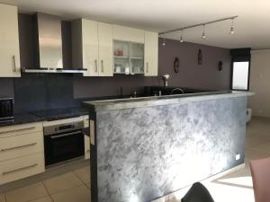 a kitchen with white cabinets and a marble counter top at Maison en pierre in Saint-Sozy +5 photos