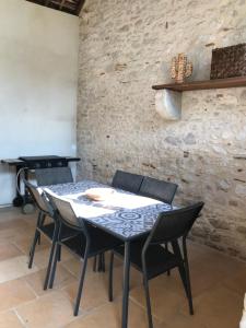 a table and chairs in a room with a stone wall at Maison en pierre in Saint-Sozy