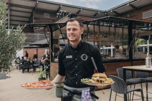 ein Mann hält ein Sandwich auf einem Teller in der Unterkunft KD 808 - Vakantiepark Kijkduin in Kraaijenstein + 7 Fotos