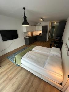 Cette chambre comprend un grand lit blanc et une cuisine. dans l'établissement Fred&Moris Apartments, à Poznań