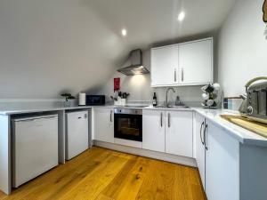 a kitchen with white cabinets and a wooden floor at New Modern Studio in Chandlers Ford with Parking in Chandlers Ford +7 photos