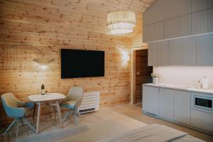 a kitchen with a table and a tv on a wall at WhiteWood Noszvaj in Noszvaj