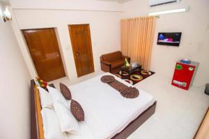 a bedroom with a bed and a chair and a television at Suite Palace in Dhaka