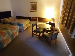 a hotel room with a table and chairs and a bed at Centennial Motel in Kindersley