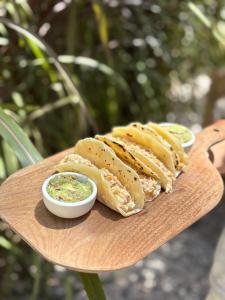 何塞伊格纳西奥Pura vida hostel的木盘上放着三个三明治，配有蘸酱。