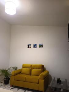 a yellow couch in a living room with three pictures on the wall at Casa Xico 424- Centro, Xicotepec, Puenlo Magico in Xicotepec de Juárez