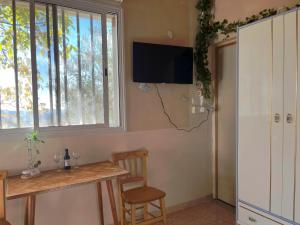 a room with a table and a tv on the wall at Olive Grove Cottage Guest house in Kouka