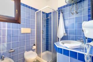 ein blau gefliestes Bad mit einem WC und einer Dusche in der Unterkunft Appartamenti Tiffany in San Teodoro + 92 Fotos