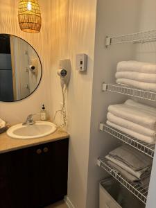 ein Badezimmer mit Waschbecken, Spiegel und Handtüchern in der Unterkunft Ski in out condo sur la montagne in Bromont