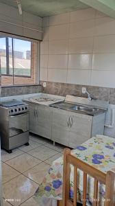 een keuken met een fornuis, een wastafel en een tafel bij Residencial Roma AP01 in Capão da Canoa