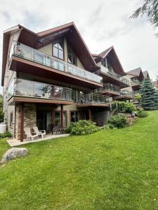 ein großes Haus mit grünem Rasen davor in der Unterkunft Ski in out condo sur la montagne in Bromont