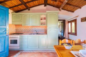 eine Küche mit grünen Schränken und einem Holztisch in der Unterkunft Appartamenti Tiffany in San Teodoro