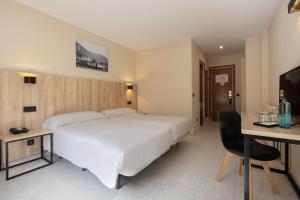 a hotel room with a large white bed and a desk at Hotel Encamp by Nexta in Encamp