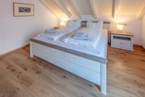 ein großes weißes Bett in einem Zimmer mit Holzböden in der Unterkunft Jolie's Cottage in Iznang