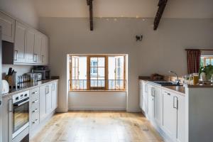 a kitchen with white cabinets and a wooden floor at Lower Marsh Farm B&B in Saltash +9 photos