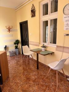 een kamer met een tafel en stoelen en een klok bij Amicii apartman in Makó