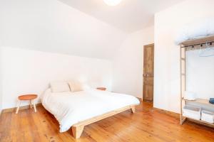 a bedroom with a white bed and a wooden floor at Ce Petit Penty in Douarnenez