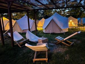 Un grupo de tiendas de campaña en el césped con sillas y mesas en O Pedrouzo Base Camp, en O Pino 