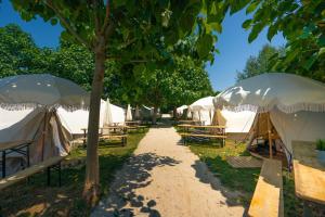 un grupo de tiendas de campaña con mesas y árboles en O Pedrouzo Base Camp, en O Pino 