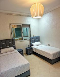 a bedroom with two beds and a chandelier at Nobilium in Meknès