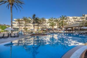 a pool at the resort with palm trees and buildings at Barceló Corralejo Bay - Adults Only in Corralejo