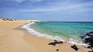 a beach with the ocean and rocks in the sand at Barceló Corralejo Bay - Adults Only in Corralejo
