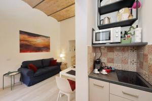 Una cocina y sala de estar con sofá y microondas. en Colosseo Mon Amour, en Roma
