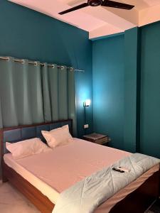 a bedroom with a bed with a blue wall at Midtown Retreat in Dibrugarh