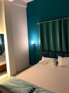 a bedroom with a bed with a green headboard at Midtown Retreat in Dibrugarh