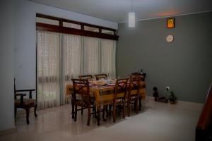 a dining room with a table and chairs and a clock at Palm Grove Bandarawela in Bandarawela