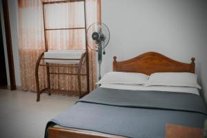 a bedroom with a bed with a fan and a chair at Palm Grove Bandarawela in Bandarawela