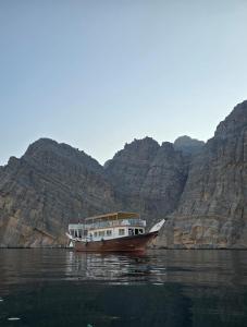 ディバにあるMusandam Starlight Dhow Cruiseの山を背景に水上の船 +39枚の写真