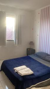a bedroom with a blue bed with two towels on it at Casa com garagem 4 pessoas in Ponta Grossa