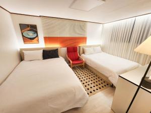 a small room with two beds and a red chair at New Sale 프리미엄 대치 강남 The Premium Daechi Gangnam in Seoul