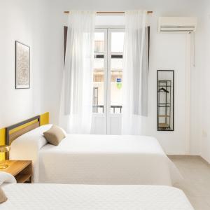 two beds in a white room with a window at Casa Antares in Granada
