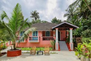 a pink house with chairs and a table in front of it at The Village Casa in Aldona