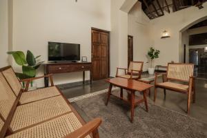 a living room with chairs and a table and a tv at The Village Casa in Aldona
