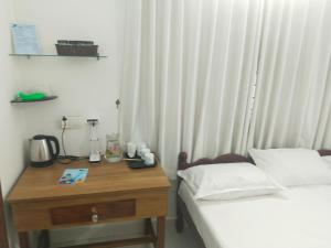 a bedroom with a bed and a wooden table with a desk at Willy's Home Stay in Parūr