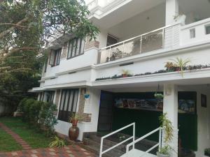 a white house with a green door and a balcony at Willy's Home Stay in Parūr +2 photos