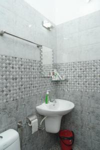 a bathroom with a white sink and a toilet at Willy's Home Stay in Parūr