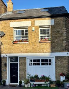 a brick house with a white garage and two windows at The Snug in a Quaint English Mews House in London