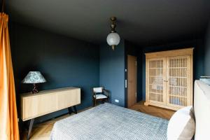a bedroom with blue walls and a desk and a bed at Riverside Architect-Designed Garden Apartment in Süderstapel